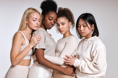 Charming multiracial young women with different ethnicity and skin posing together. Pacified black american asian and caucasian ladies leaned on each other, calm. Isolated on white