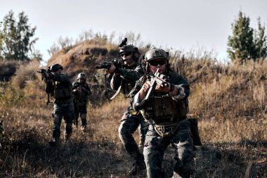 Fully Equipped Soldiers Wearing Camouflage Uniform Going To Attack Enemy, Rifles Weapons in Firing Position. Military Operation in Action, Squad Running in Mountains Field In Nature.