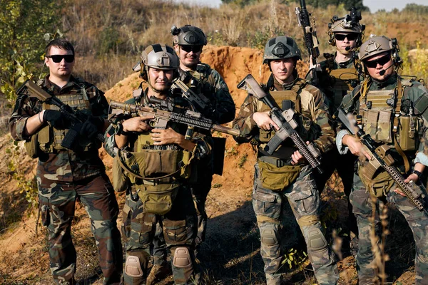 military men, group of soldiers posing at camera carrying rifle guns, weapons. The concept of military operations, special operations. team of soldiers looking at camera, friendly group of soldiers