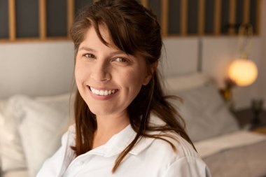 Kameraya bakıp yatakta gülümseyen kadın portresi.