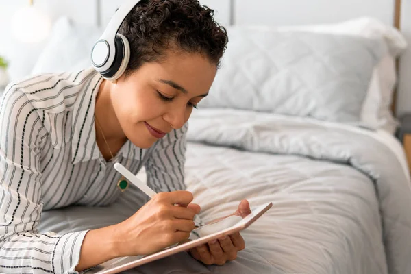 inspired woman drawing in tablet in the bedroom