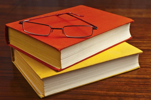 Old dusty books and glasses on the wooden table — Stock Photo, Image