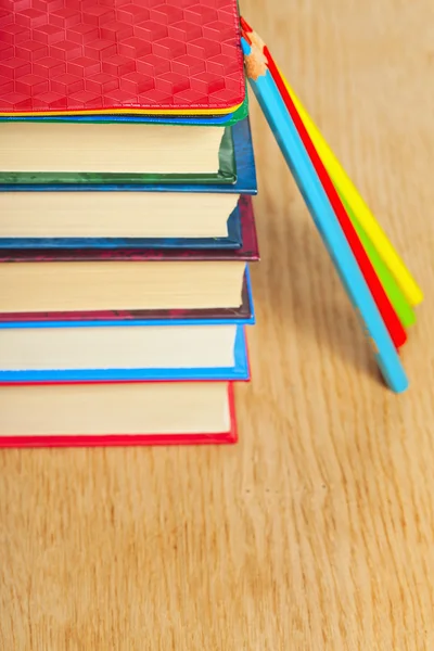 Kazık kitap ve bir ahşap yüzeye renkli kalemler. — Stok fotoğraf