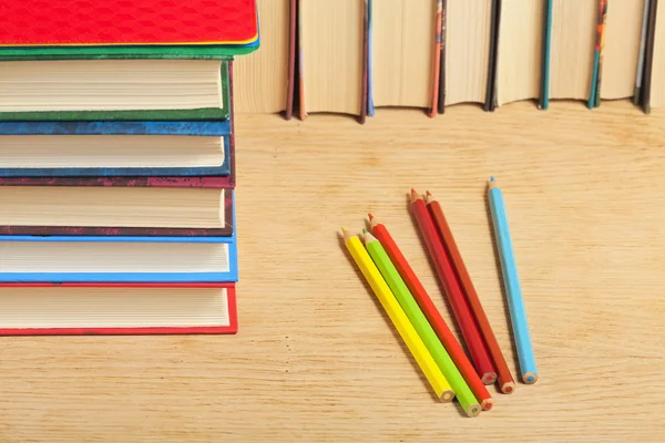 Pile de livres et crayons de couleur sur une surface en bois contre th — Photo