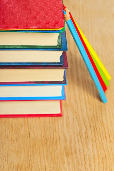 Stapel boeken en kleurpotloden op een houten ondergrond. Rechtenvrije Stockafbeeldingen