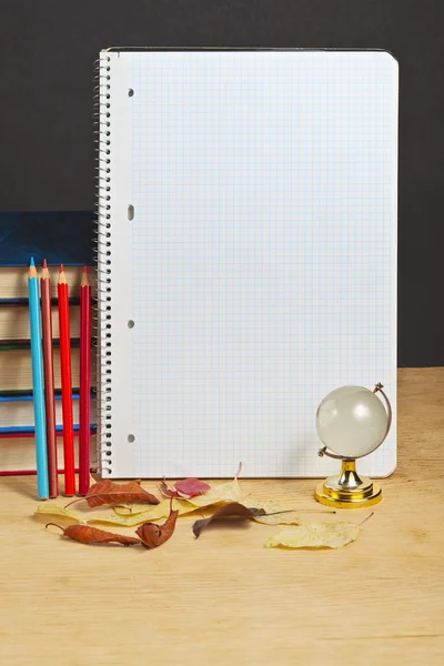Notitieboekje met kleurpotloden en globe op een houten oppervlak. — Stockfoto