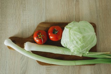 Domates, pırasa ve lahana. Ormanlık masada taze organik sebzeler.