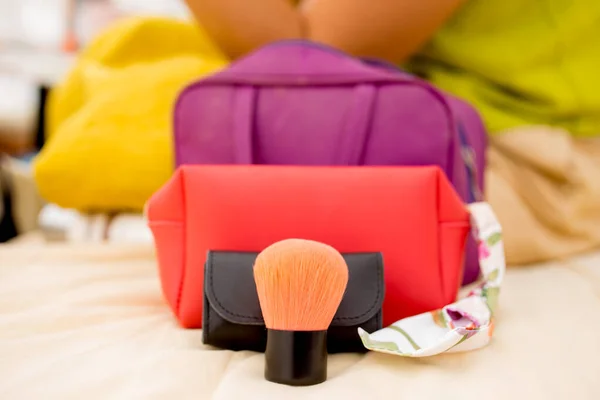 Close up makeup and cosmetic bag on bed.