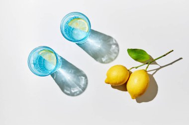 Limonlu suyu mavi bardaklarda, taze limonlarla, güneş ışığıyla ve gölgelerle detoks edin. Yaz içeceğini tazeliyorum..