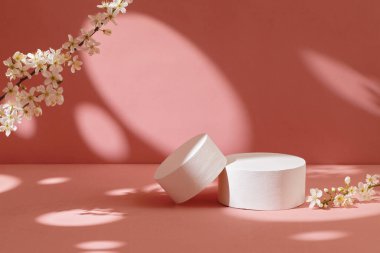 Pastel pembe arka planda çiçekli boş beyaz podyumlar. Minimum geometrik podyum. Model.