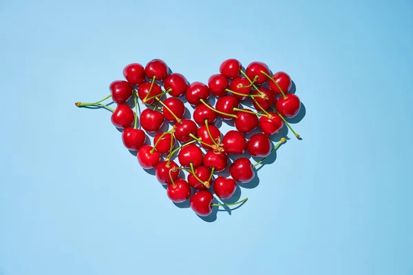 Fresh Ripe Red Cherries Arranged Heart Shape Blue Background Flat — Stock fotografie