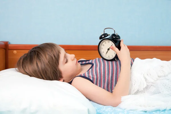 El chico en la cama con despertador — Foto de Stock