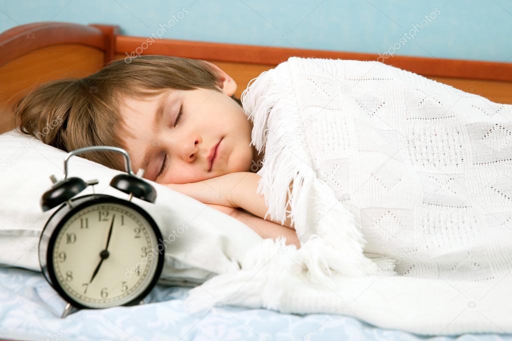 The boy in bed with wake-up clock