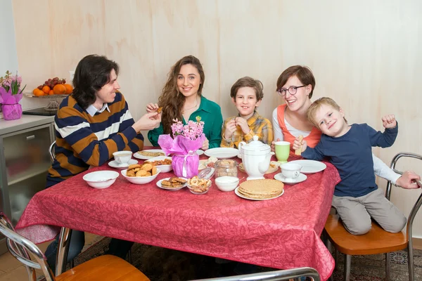 Chłopców i trzy osoby dorosłe siedzieć przy stole — Zdjęcie stockowe