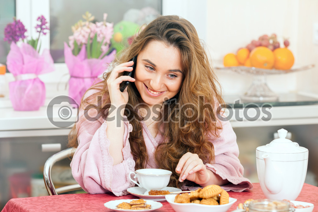 Girl speaks by phone and drinks tea