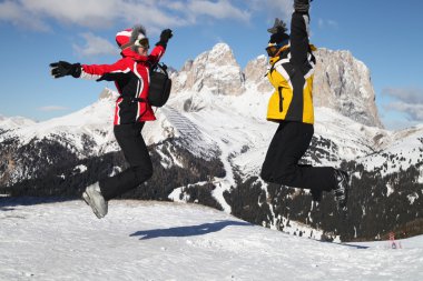 Skiers jumping against big mountain clipart