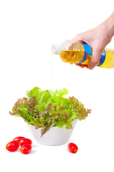 Le mani versano l'olio in insalata — Foto Stock