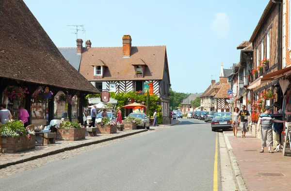 Touristen spazieren auf der Hauptstraße eines Dorfes in der Normandie — Stockfoto