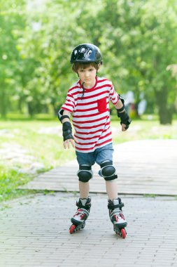 Boy on rollers in the summer park clipart