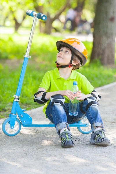 Rapaz senta-se em scooter pontapé — Fotografia de Stock