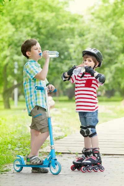 Bambini con scooter e rulli bere acqua — Foto Stock