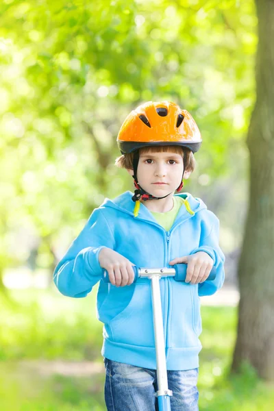 Young boy riding kick scooter in park — Stock Photo, Image