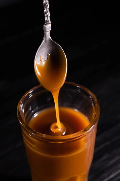 Homemade salted caramel sauce in a jar on a dark background. copy space text — Stock Photo, Image