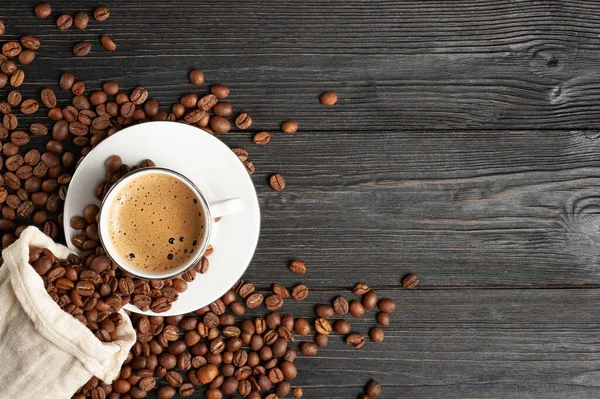 Uma xícara de café e grãos de café em um fundo de madeira. Vista superior. Espaço livre para texto . — Fotografia de Stock