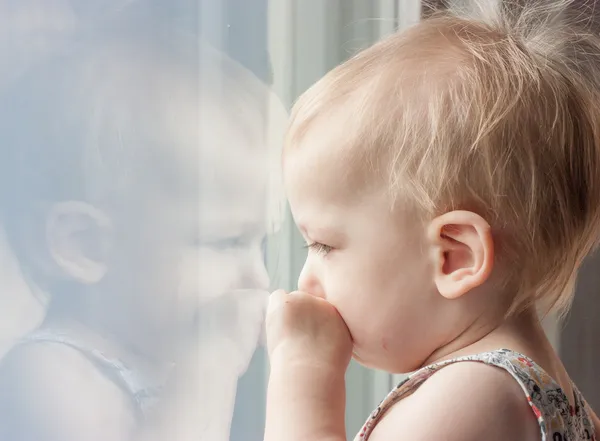 Bambino triste che guarda fuori dalla finestra — Foto Stock