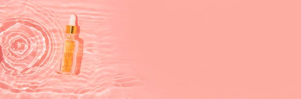 Recipiente de vidro com óleo de beleza e pipeta em água rosa — Fotografia de Stock