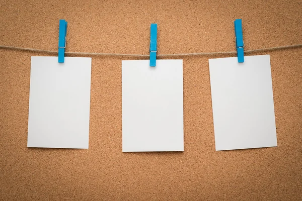 Tres tarjetas de papel memo colgando de una cuerda con cartón de corcho . Imagen De Stock