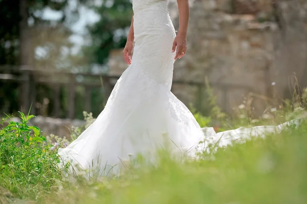 Vestido de novia sobre hierba verde natural al aire libre y fondo de piedra —  Fotos de Stock