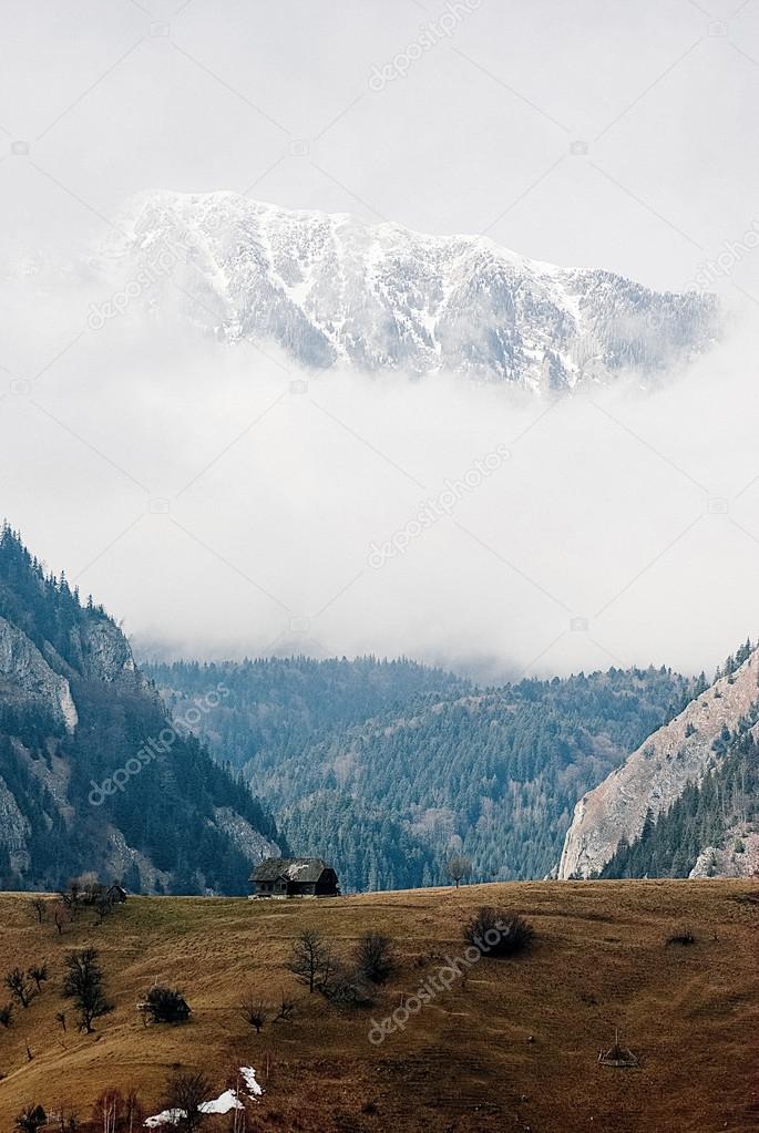 Amazing scenery of old hut and Romanian Carpathian mountains on clouds