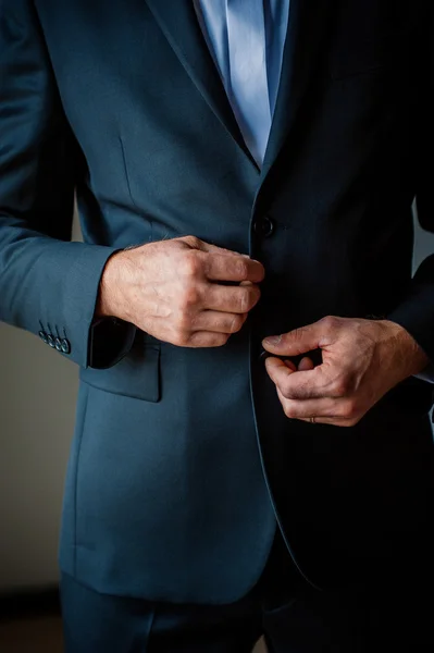 Elegantes manos de hombre en traje negro abotonando — Foto de Stock