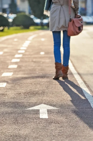 Nahaufnahme von Frauenbeinen beim Gehen auf Radweg und Pfeilschild — Stockfoto