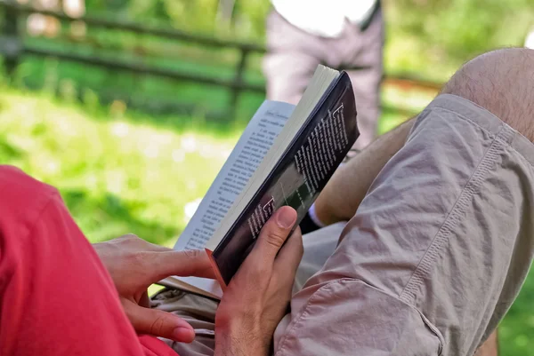 Yakın çekim adam açık oturma ve bir kitap okuma — Stok fotoğraf