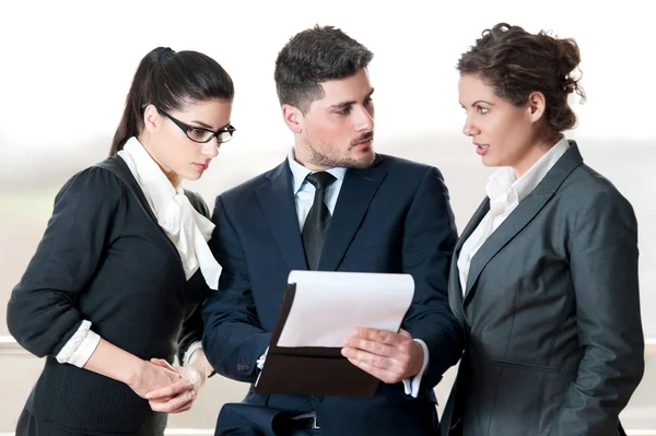 Two business women and business man discussing over a clip board — Stock Photo, Image