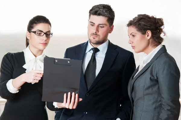 Deux femmes d'affaires et un homme d'affaires parlent sur un tableau à feuilles mobiles — Photo