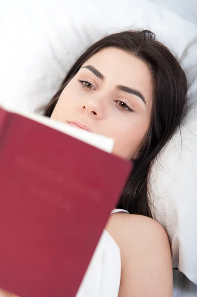 Entspannende junge schöne Frau liest im Bett — Stockfoto