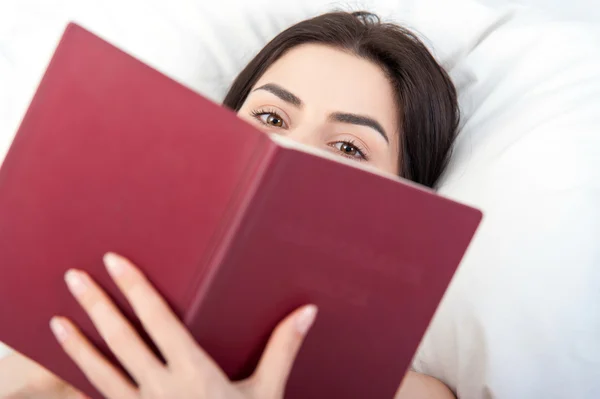 Закрыть молодую женщину, читающую в постели — стоковое фото