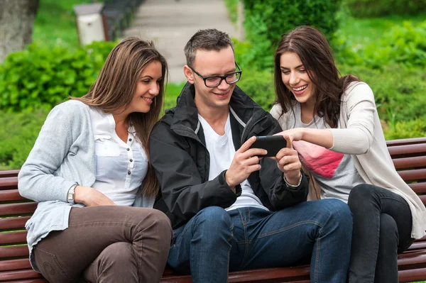 Gruppe von Freunden sitzt auf einer Bank im Park und genießt — Stockfoto