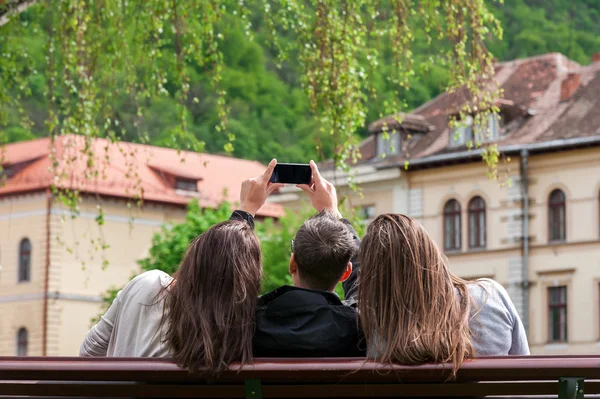 Three young friends taking photos with smartphone in the park — Stock Photo, Image