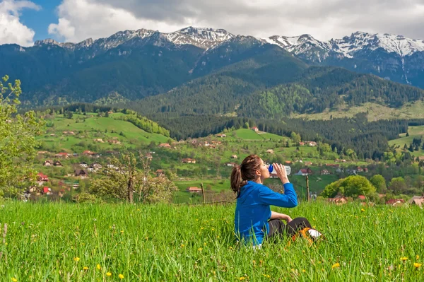 背景に美しい山の景色と丘の上に休む若い女性 — ストック写真