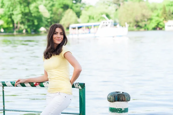 Retrato de la joven mujer hermosa contra el lago en el parque de la ciudad de verano . — Foto de Stock