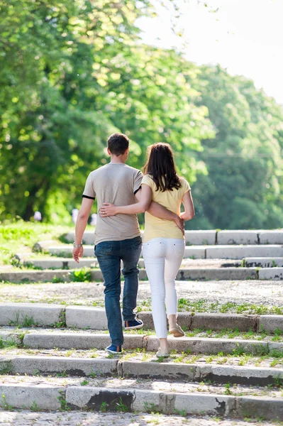 Jonge vrouw en man lopen in het stadspark hand in hand — Stockfoto