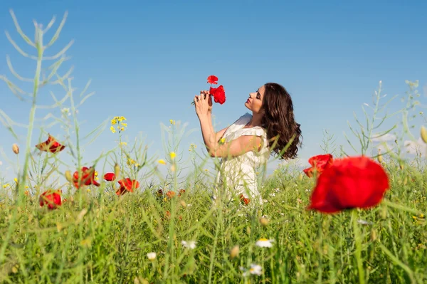 ケシの花束を保持している白いドレスでケシ畑で美容女性 — ストック写真