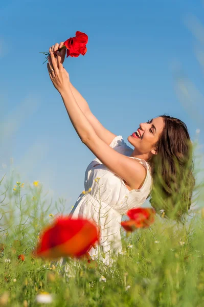 Chica de verano en el campo de amapola sosteniendo un ramo de amapolas — Foto de Stock