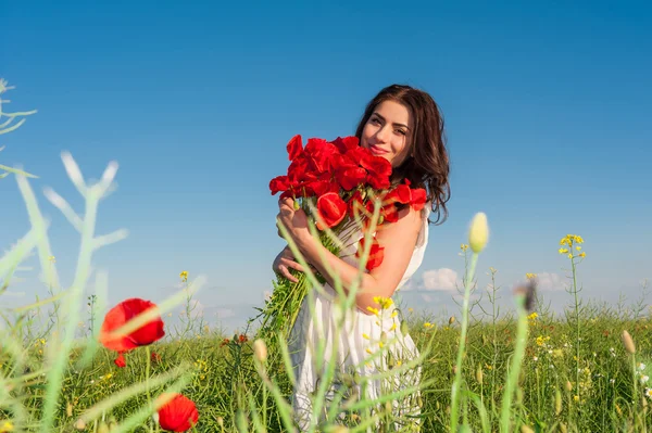年轻美丽的姑娘在田里拿着罂粟花束. — 图库照片