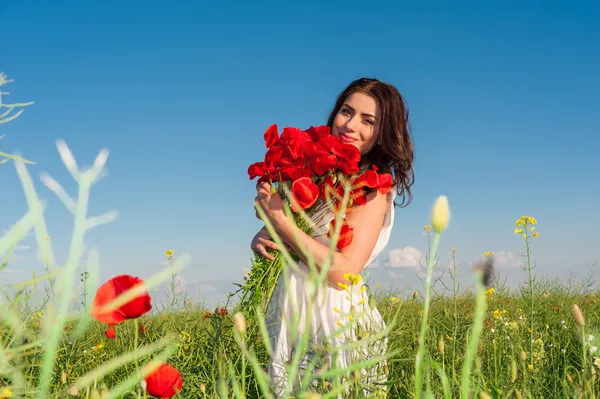 Jovem menina bonita no campo com um buquê de papoilas . — Fotografia de Stock