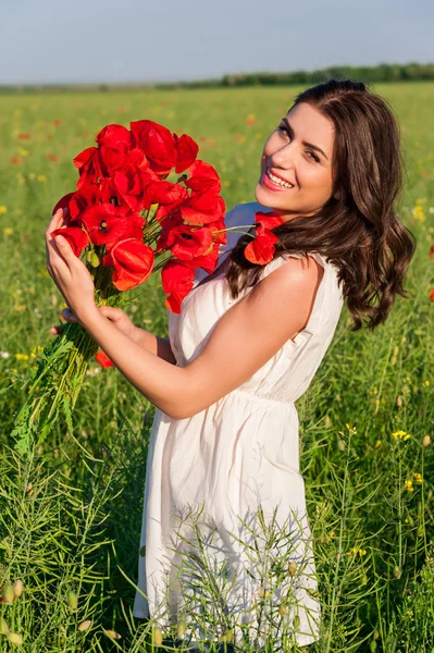 Portret van een mooie jonge vrouw met klaprozen in het veld met een papaverboeket. — Stockfoto